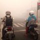 Foto dua pengendara sepeda motor berhenti di lampu merah Jalan Tjilik Riwut Palangka Raya di tengah kabut asap tebal akibat karhutla.