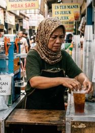 Pelaku UMKM minuman mengemas pesanan di kios sederhana di tengah kenaikan harga cup plastik dan bahan baku yang meningkatkan biaya produksi usaha kecil.