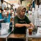 Pelaku UMKM minuman mengemas pesanan di kios sederhana di tengah kenaikan harga cup plastik dan bahan baku yang meningkatkan biaya produksi usaha kecil.