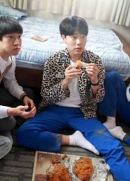 Foto empat remaja sedang menonton bersama sambil makan ayam goreng di sebuah kamar.