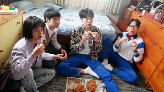 Foto empat remaja sedang menonton bersama sambil makan ayam goreng di sebuah kamar.