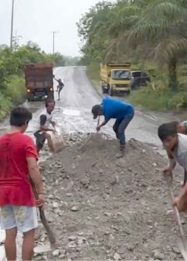 Foto warga sedang menimbun ruas jalan nasional yang rusak parah di Kalimantan Tengah.