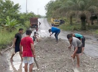 Foto warga sedang menimbun ruas jalan nasional yang rusak parah di Kalimantan Tengah.