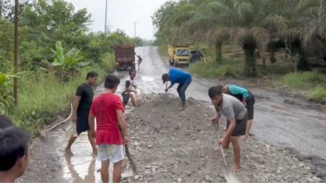 Foto warga sedang menimbun ruas jalan nasional yang rusak parah di Kalimantan Tengah.