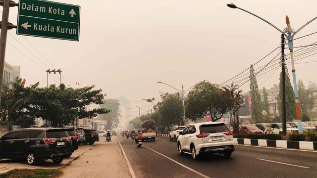 Suasana Kota Palangka Raya diselimuti kabut asap tebal dengan langit berwarna kemerahan akibat kebakaran lahan gambut.
