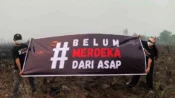 WALHI Kalimantan Tengah membentangkan spanduk kampanye di lahan bekas terbakar yang diduga akibat aktivitas korporasi.